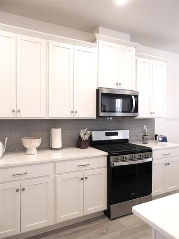 a kitchen with white cabinets and appliances
