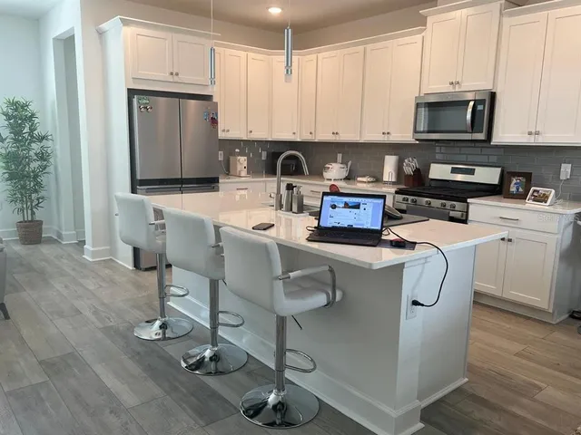 a kitchen with stainless steel appliances granite countertop a stove a sink a microwave and a refrigerator