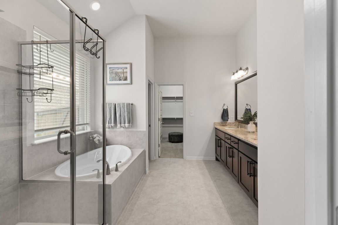 232 Silver Pass Kyle, TX 78640 - Photo 22 of 39 Soak the day away in your garden tub or enjoy the sleek glass walk-in shower. This spa inspired bathroom offers dual vanities, granite counters, and plenty of natural light.