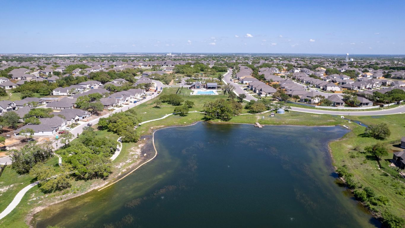 232 Silver Pass Kyle, TX 78640 - Photo 36 of 39 Breathtaking aerial shot showcasing the peaceful pond, winding walking trails, and resort-style pool all nestled within the heart of the neighborhood. The serenity of nature meets the convenience of suburban living.
