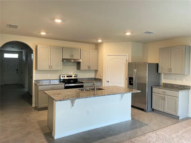 a large kitchen with stainless steel appliances granite countertop a stove a sink and a refrigerator