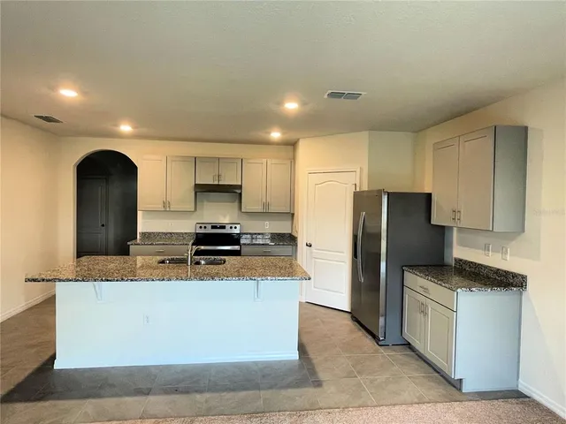 a kitchen with stainless steel appliances granite countertop a stove a sink and a refrigerator