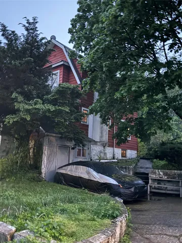 a view of a house with a yard plants and a large tree