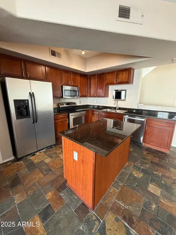 a kitchen with stainless steel appliances granite countertop a stove refrigerator and sink