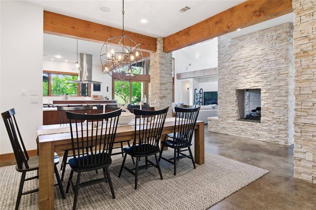 1138 Bancroft Road Keller, TX 76248 - Photo 8 of 39 Open-concept dining area featuring exposed wood beams, a stacked stone fireplace, and polished concrete flooring
