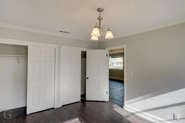 a view of a hallway with wooden floor and chandelier