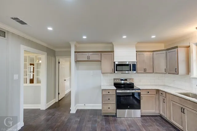 a kitchen with granite countertop a refrigerator stove and microwave