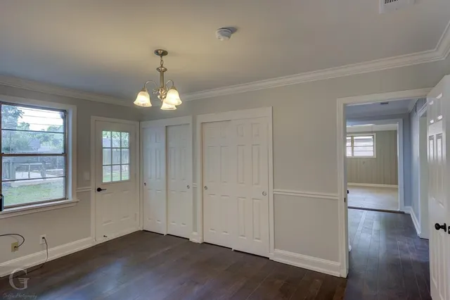 an empty room with wooden floor cabinet and windows