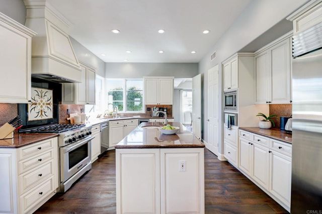 a large kitchen with stainless steel appliances kitchen island granite countertop a stove and a sink