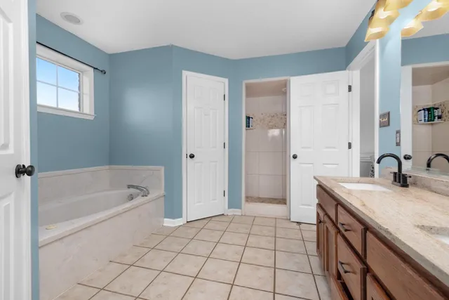 a spacious bathroom with a granite countertop sink a mirror a shower and a bathtub