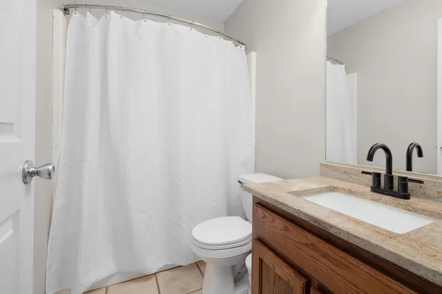 a bathroom with a granite countertop sink toilet and a mirror