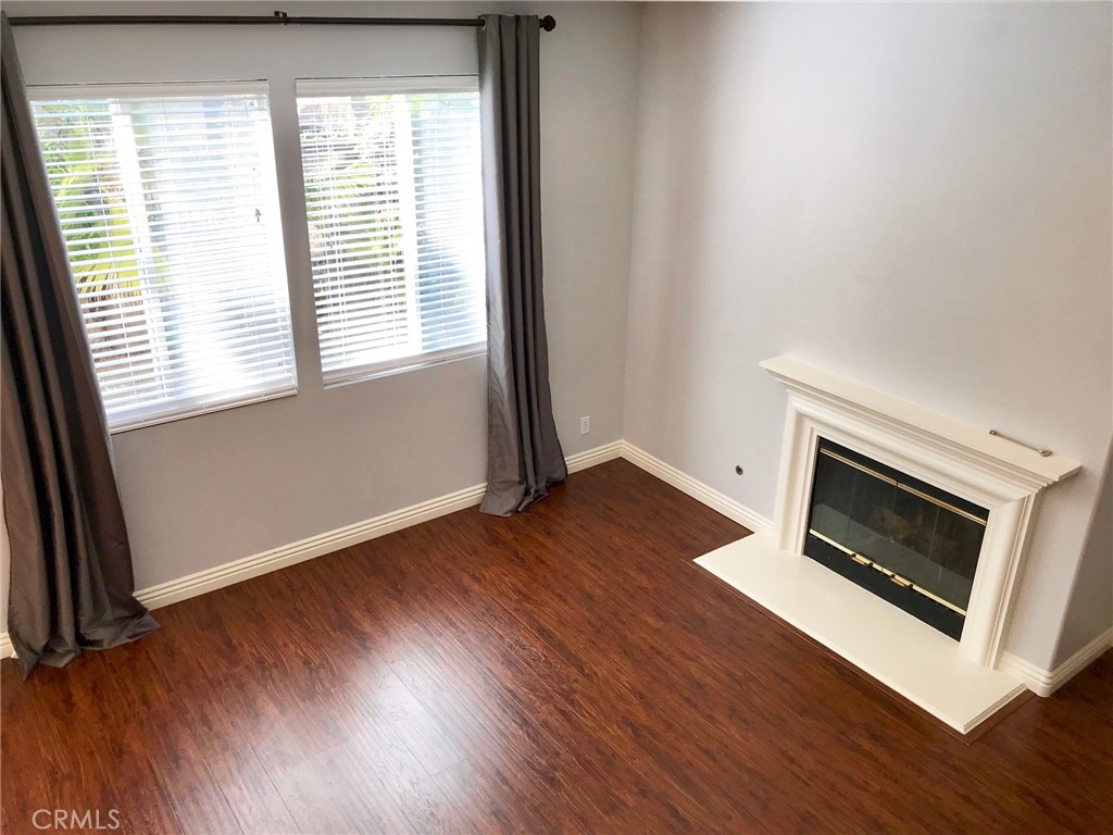 15 Brookhollow Irvine, CA 92602 - Photo 4 of 8 an empty room with wooden floor and fireplace