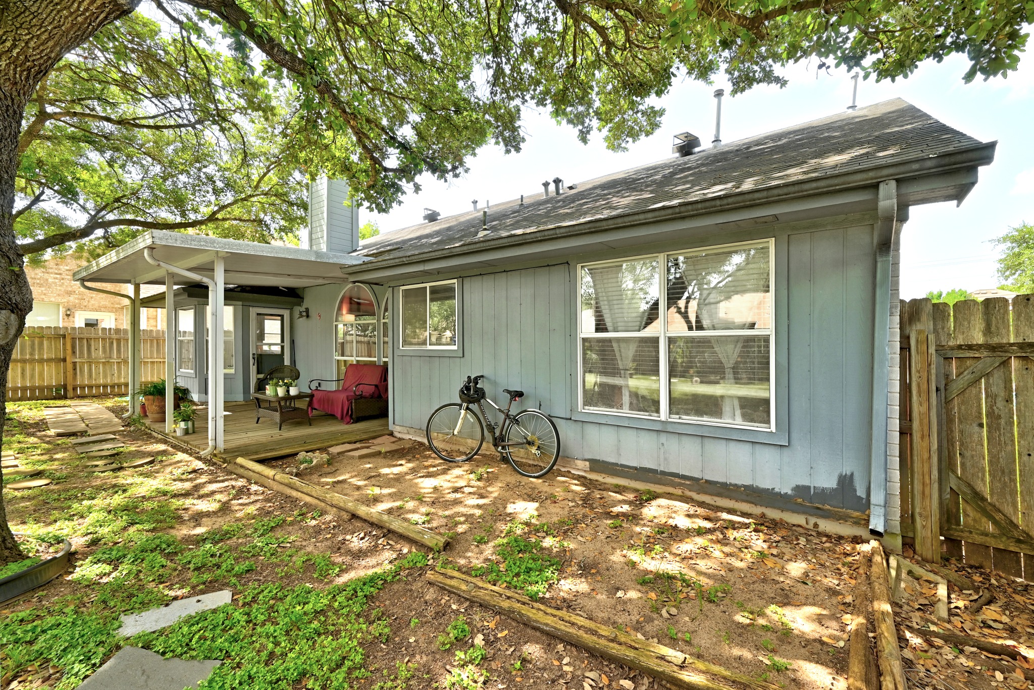 6412 Colton-Bluff Springs Road Austin, TX 78744 - Photo 25 of 27 A spacious backyard with mature trees, a wooden deck, and a fenced perimeter for privacy.