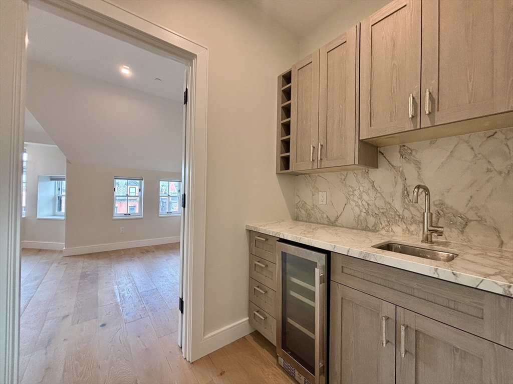 246 Newbury Street, Unit PH Boston, MA 02116 - Photo 13 of 22 a kitchen with stainless steel appliances granite countertop a sink and cabinets with wooden floor