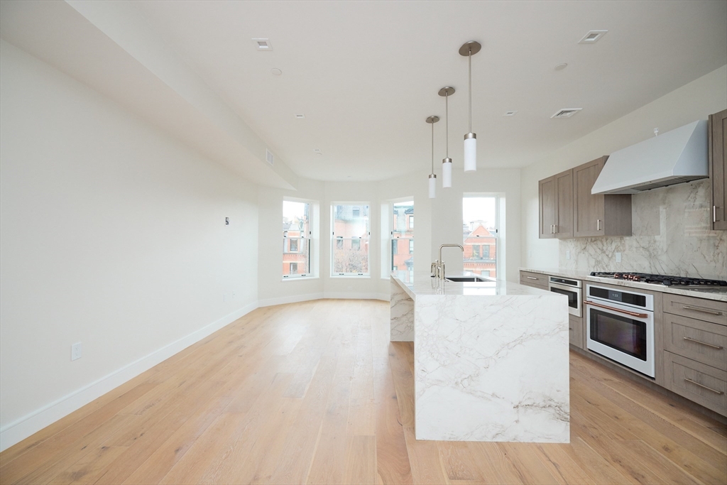 246 Newbury Street, Unit PH Boston, MA 02116 - Photo 5 of 22 a large kitchen with cabinets wooden floor and stainless steel appliances