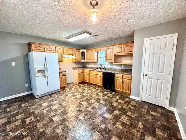 a large kitchen with kitchen island granite countertop a stove refrigerator and microwave