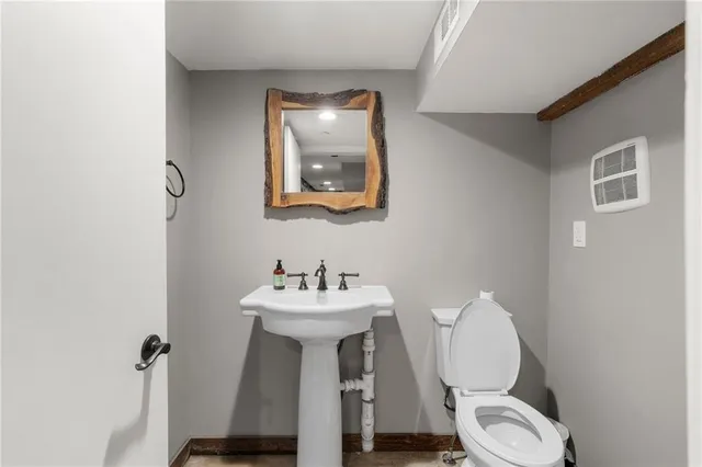 a bathroom with a toilet a sink and mirror