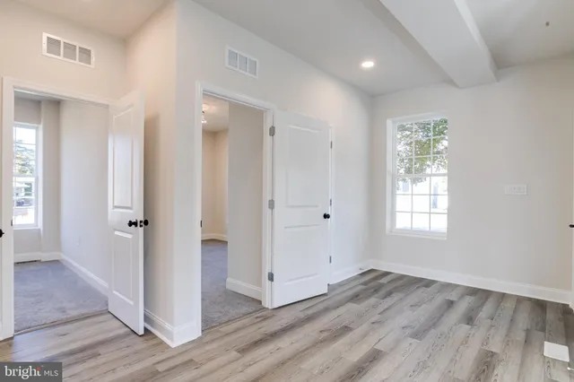 an empty room with wooden floor fan and windows