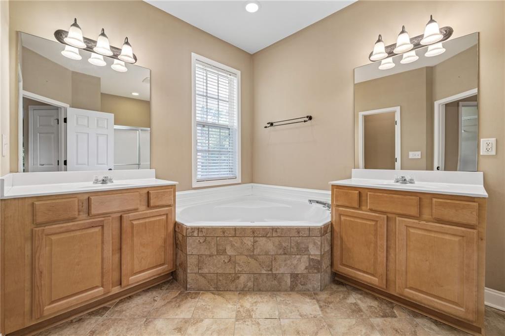 7913 Pea Ridge Road Lula, GA 30554 - Photo 16 of 51 a spacious bathroom with a double vanity sink large mirror and a bathtub