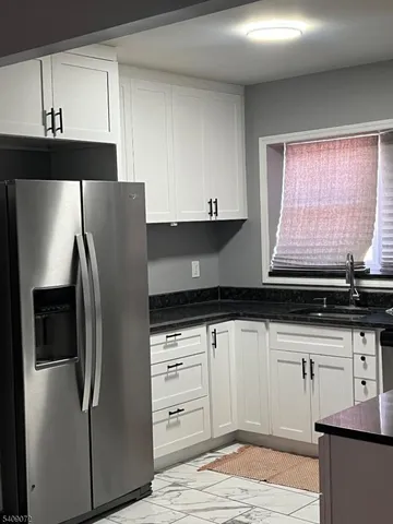 a kitchen with granite countertop a refrigerator and a sink