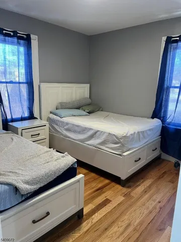 a bed sitting in a bedroom next to a window with wooden floor