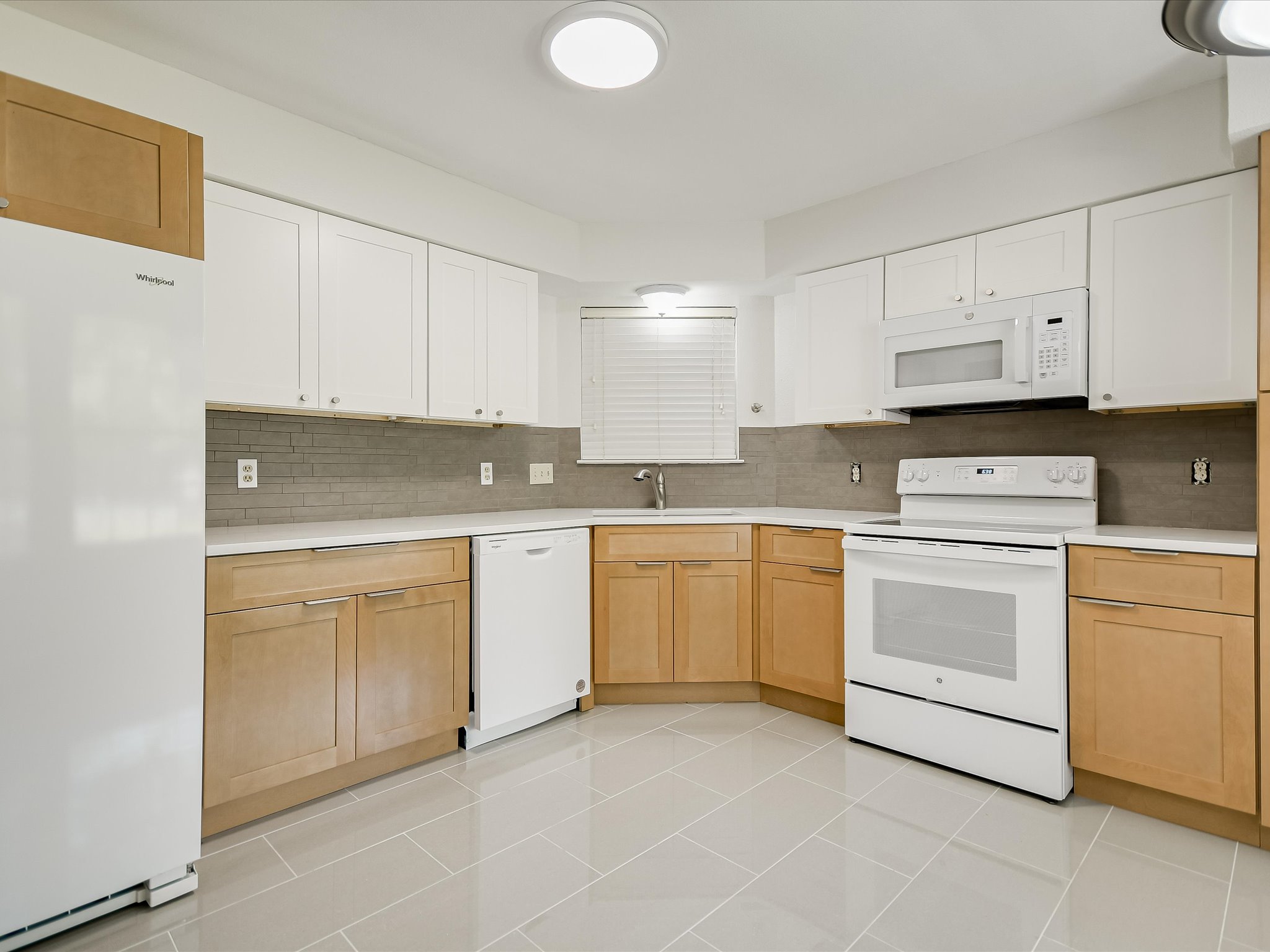 1704 Waterloo Trail, Unit B Austin, TX 78704 - Photo 8 of 10 Dual tone kitchen featuring white appliances, light countertops, decorative backsplash, light tile patterned floors, and two tone color scheme