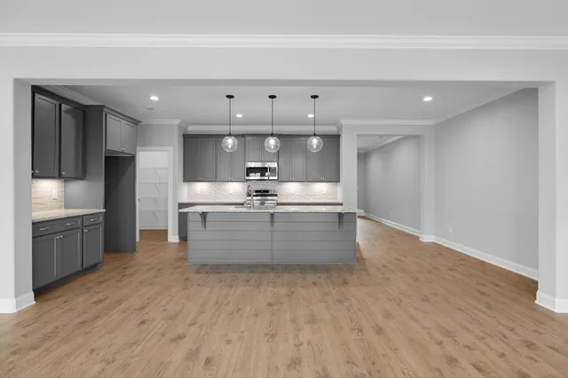 a large kitchen with stainless steel appliances kitchen island granite countertop a large counter top and wooden floors