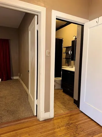 a view of a hallway with wooden floor and a living room