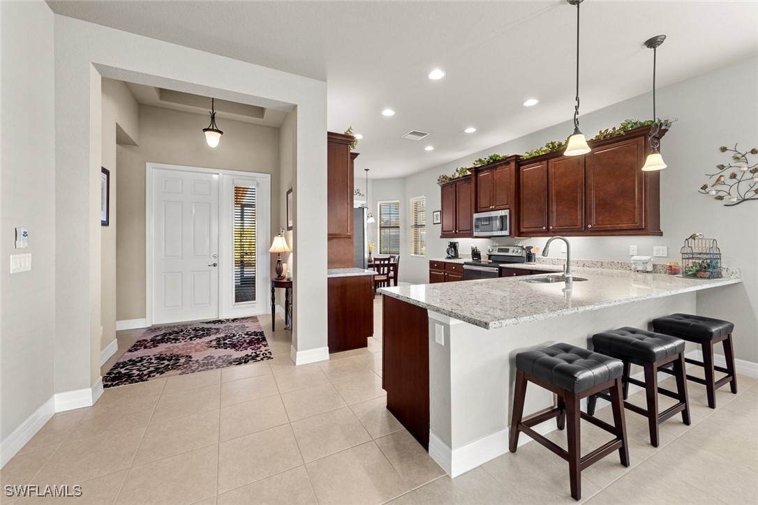11652 Meadowrun Circle Fort Myers, FL 33913 - Photo 4 of 38 a kitchen with kitchen island granite countertop wooden cabinets and a refrigerator