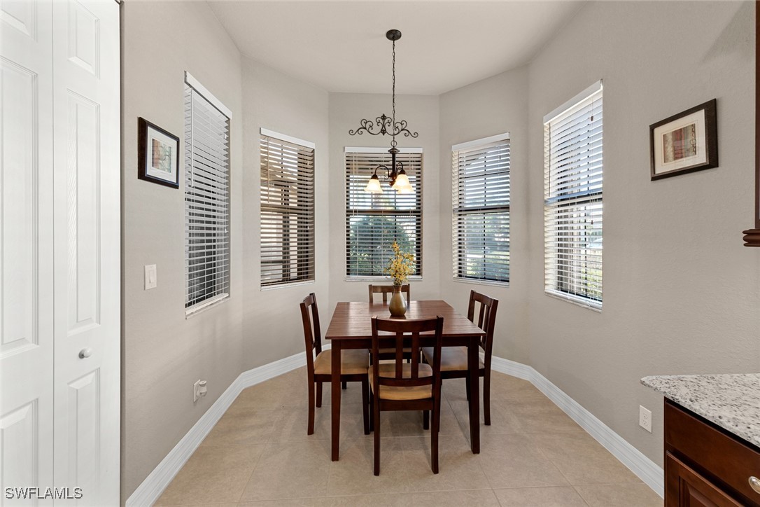 11652 Meadowrun Circle Fort Myers, FL 33913 - Photo 7 of 38 a dining room with wooden floor a chandelier a wooden table and chairs