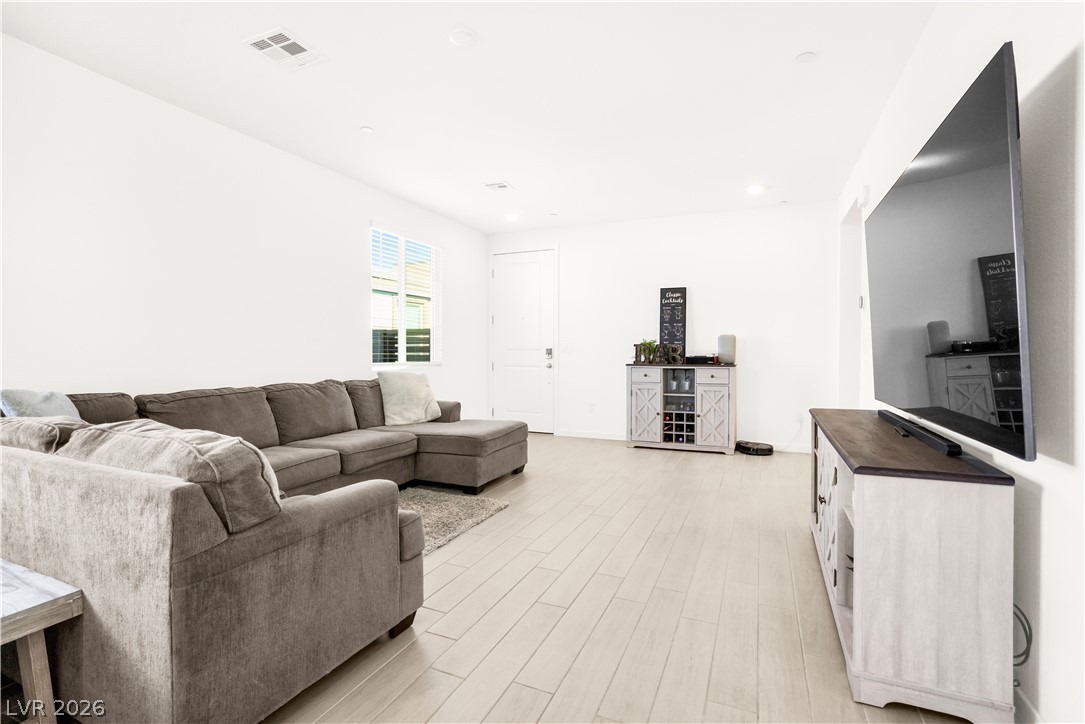 9398 Noble Fir Rdg Court Las Vegas, NV 89143 - Photo 7 of 36 A well-proportioned living room featuring light wood flooring and bright white walls.