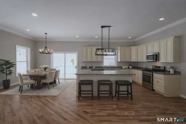 a open kitchen with stainless steel appliances granite countertop a stove and a wooden floors