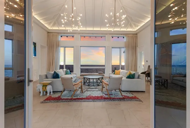 a living room with furniture a large window and a chandelier