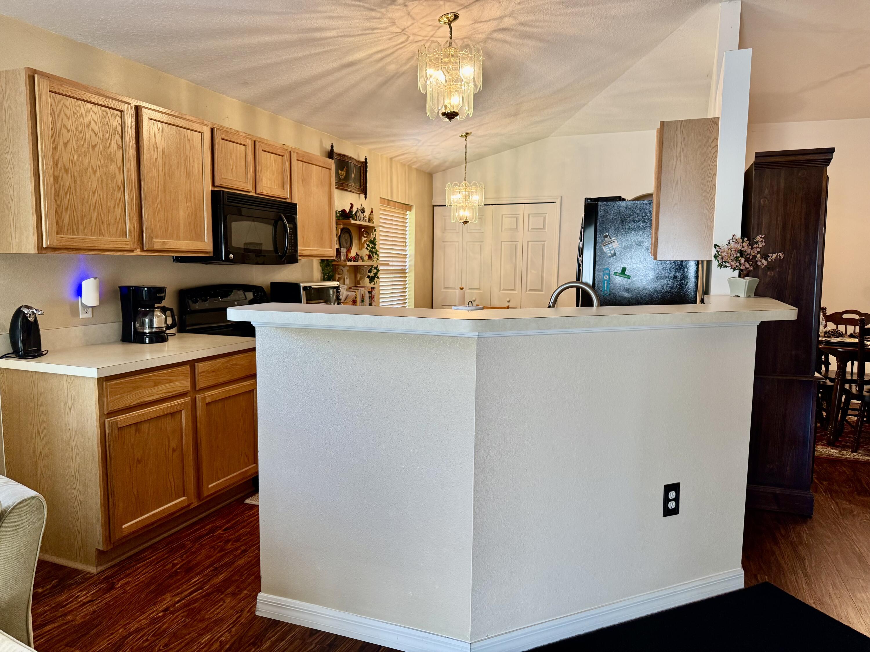 527 Southeast 38th Avenue Okeechobee, FL 34974 - Photo 10 of 30 a kitchen with stainless steel appliances a stove top oven a sink a microwave a refrigerator a dining table and chairs with wooden floor