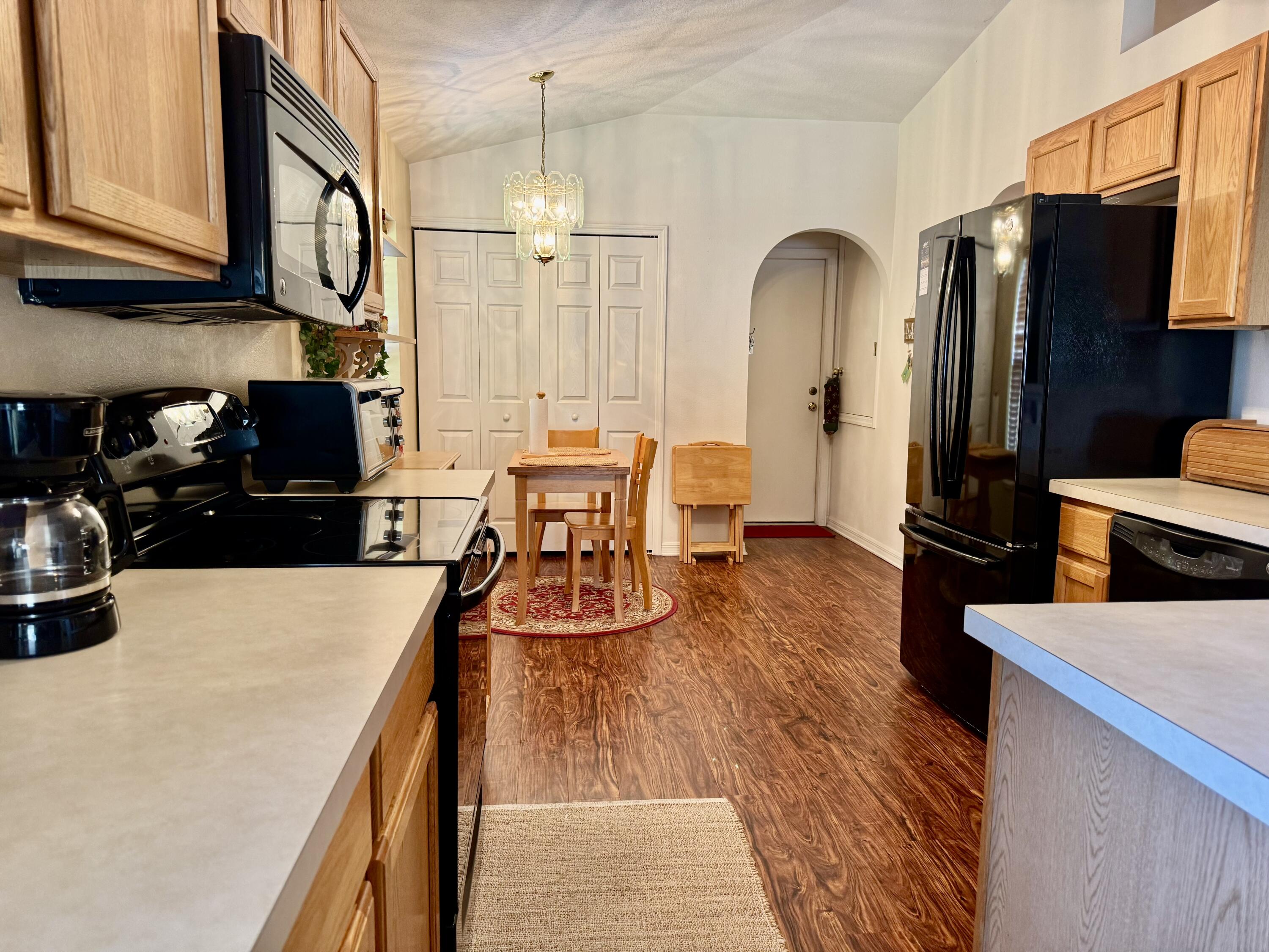 527 Southeast 38th Avenue Okeechobee, FL 34974 - Photo 9 of 30 a kitchen with stainless steel appliances granite countertop a refrigerator a stove top oven a sink dishwasher and wooden cabinets with wooden floor
