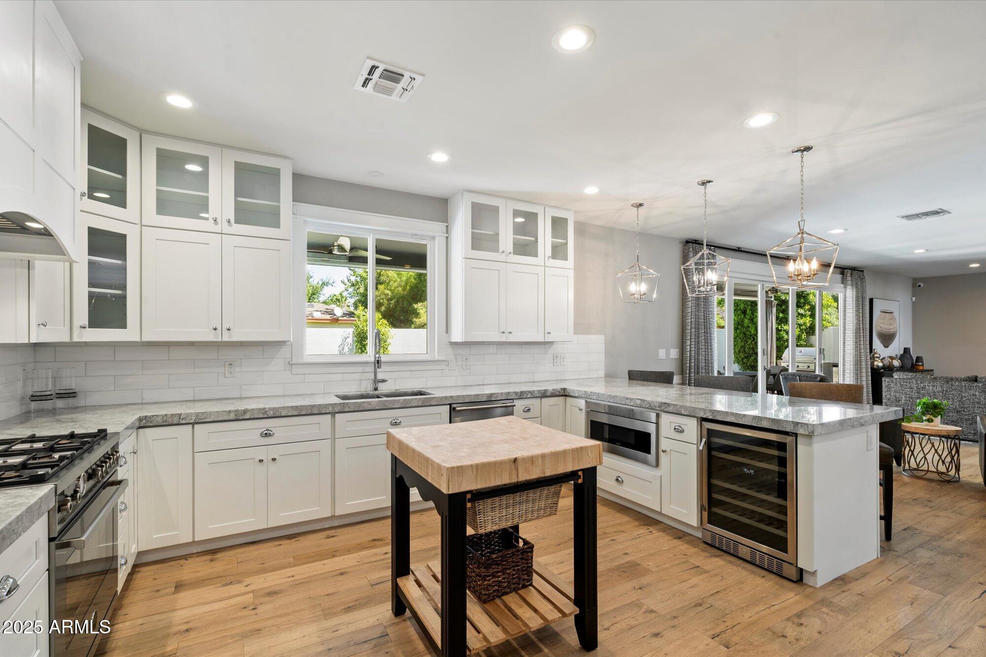 3810 East Devonshire Avenue Phoenix, AZ 85018 - Photo 11 of 34 a kitchen with a stove a sink a kitchen island with chairs and wooden floor