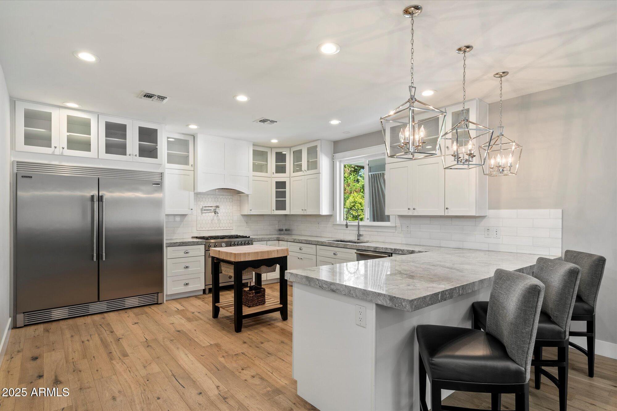 3810 East Devonshire Avenue Phoenix, AZ 85018 - Photo 9 of 34 a kitchen with kitchen island a dining table chairs sink and cabinets