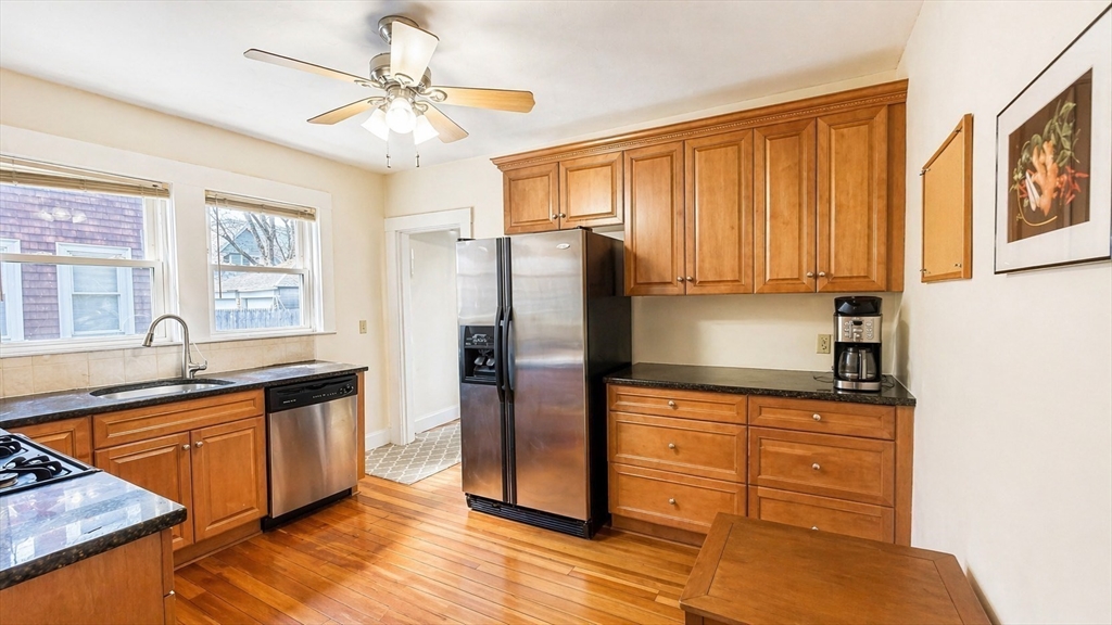 86 Howard Street, Unit 1 Waltham, MA 02451 - Photo 7 of 22 a kitchen with stainless steel appliances granite countertop a refrigerator a sink dishwasher stove and oven with wooden cabinets