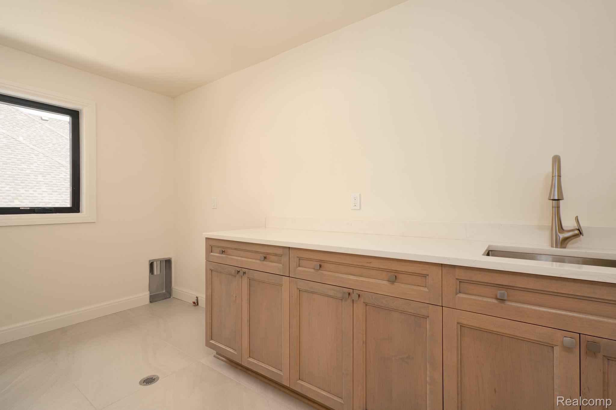 3836 Coachwood Lane Rochester, MI 48309 - Photo 63 of 82 Utility room featuring light wood-finish cabinetry, a light-toned countertop, and an undermount sink with a gooseneck faucet