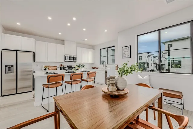 a kitchen with a dining table chairs and refrigerator