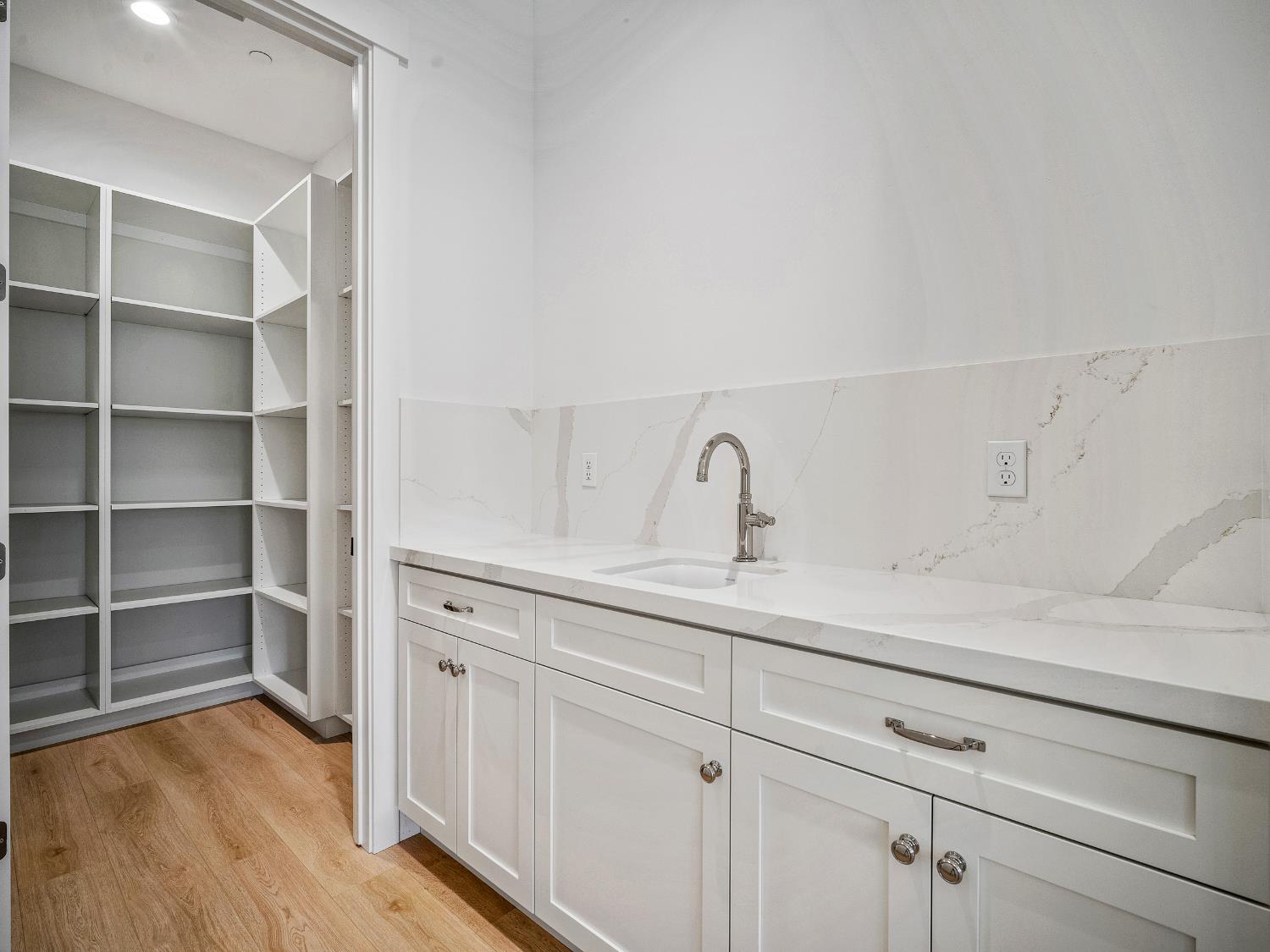 8118 Bridger Lane Shingle Springs, CA 95682 - Photo 42 of 59 a kitchen with white cabinets and wooden floor