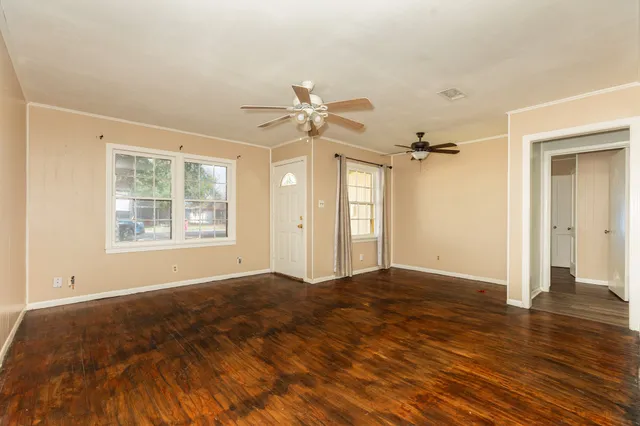 a view of an empty room with window and wooden floor