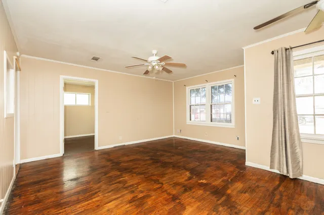 an empty room with wooden floor and windows