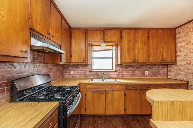 a kitchen with a sink stove top oven and cabinets