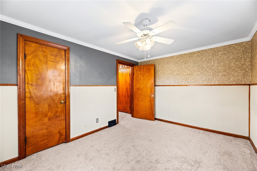 4556 Fishcreek Road Stow, OH 44224 - Photo 14 of 41 Unfurnished room with carpet flooring, ornamental molding, wallpapered walls, a wainscoted wall, and ceiling fan