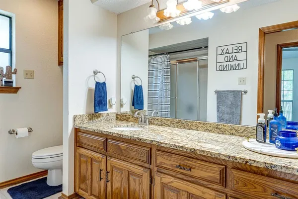 a bathroom with a granite countertop sink a toilet and a mirror