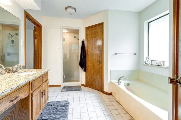 a bathroom with a granite countertop tub sink and a mirror