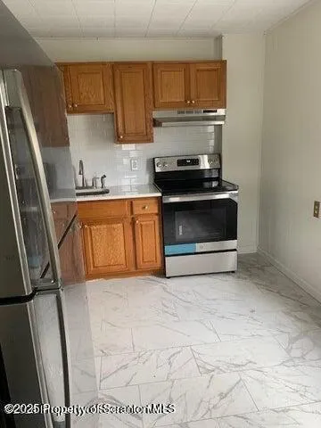 a kitchen with stainless steel appliances granite countertop a stove a sink and a refrigerator