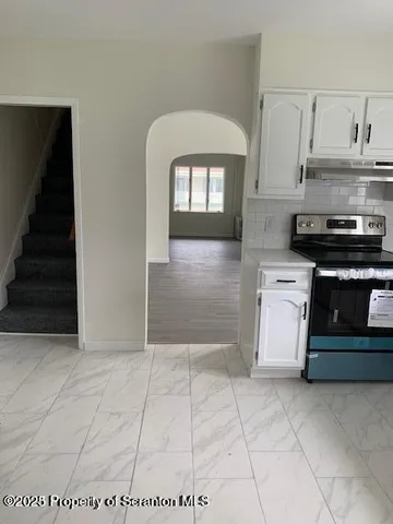 a kitchen with granite countertop a stove a sink and a microwave
