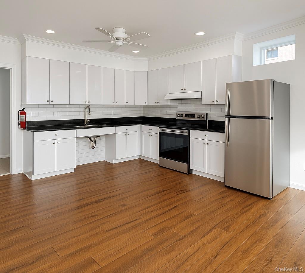 422 Broadway, Unit 6 Monticello, NY 12701 - Photo 2 of 7 a kitchen with stainless steel appliances granite countertop a refrigerator sink and white cabinets